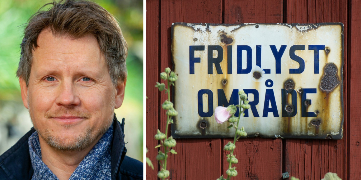 En man med kort brunt hår iklädd blå halsduk och mörk jacka dyker upp till vänster, medan en vittrad metallskylt med texten "FRIDLYST OMRÅDE" i mörkblått är monterad på en röd trävägg med blommor i förgrunden till höger.