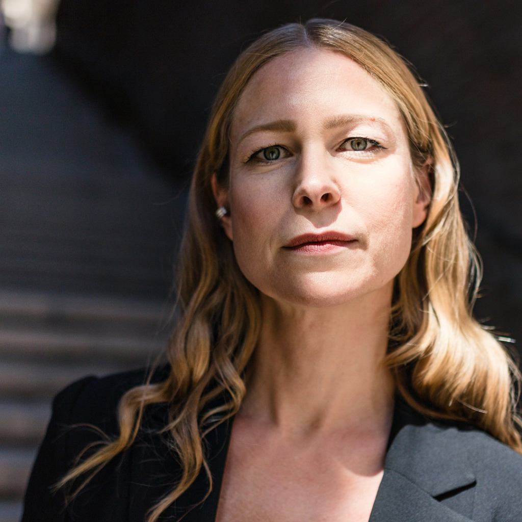 Karin Gyllenring, en kvinna med långt ljust hår, står i en solbelyst trappa