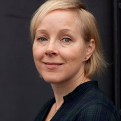 En kvinna med kort blont hår ler mot kameran.